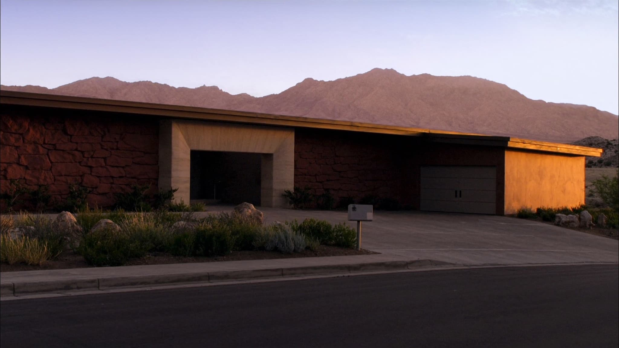 Desert luxury home with low golden light raking across red rock, Nevada